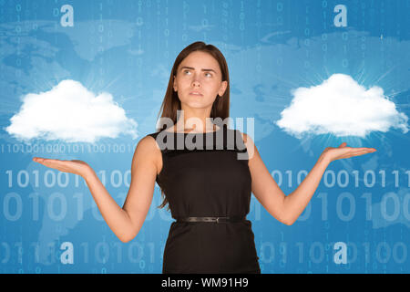 Businesswoman holding two white clouds as if chosing. On blue background with faint world map and binary code rows Stock Photo
