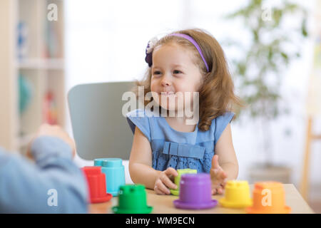 Child with teacher playing with educational cup toys in daycare Stock Photo