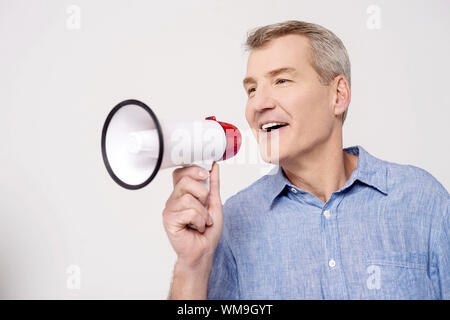 Happy man making announcement over a bullhorn Stock Photo