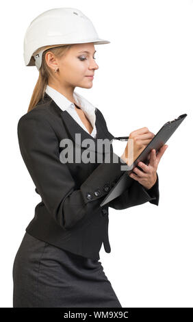 Businesswoman wearing hard hat, writing on clipboard. Isolated over white background Stock Photo