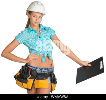 Woman in hard hat and tool belt standing akimbo, holding clipboard down at distance, looking at camera. Isolated on white background Stock Photo