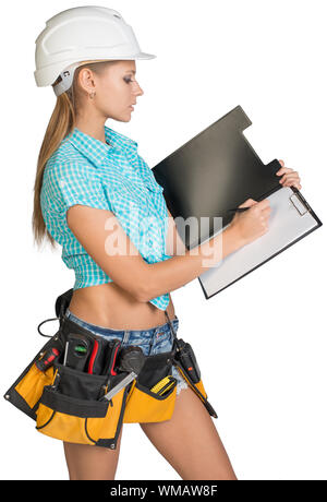 Woman in hard hat and tool belt writing on blank clipboard. Isolated on white background Stock Photo