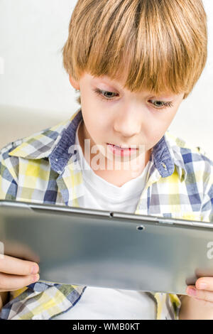 School boy with electronic tablet sitting in hall Stock Photo