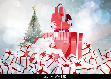 Santa standing in large gift against light glowing dots on blue Stock Photo