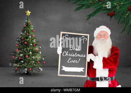 Composite image of santa claus showing blackboard against grey room Stock Photo