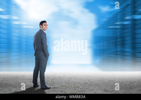 Smiling businessman standing against server hallway in desert setting Stock Photo