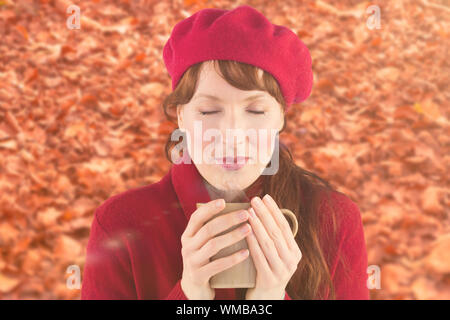 Woman holding a warm cup against autumn leaves on the ground Stock Photo