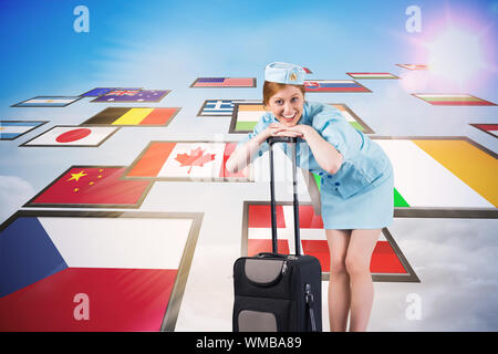 Pretty air hostess smiling at camera against screen collage showing international flags Stock Photo