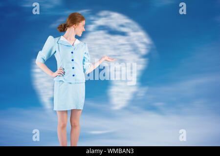 Pretty air hostess presenting with hand against digitally generated globe in sky Stock Photo