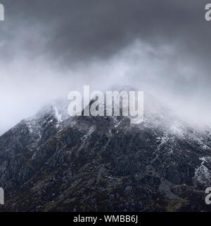 Stunning detail landscape images of snowcapped Pen Yr Ole Wen mountain in Snowdonia during dramatic Winter storm Stock Photo