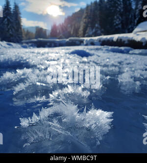 Snowflakes as a snow butterflies over frozen icy river. Frosty nature background. Stock Photo