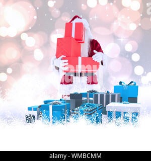 Santa covers his face with presents against white glowing dots on grey Stock Photo