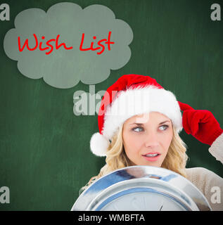 Happy festive blonde with clock against green chalkboard Stock Photo