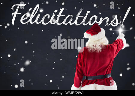 Santa claus points at something against blackboard Stock Photo