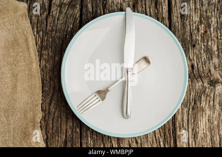 Plate and cutlery on rustic wooden table with canvas. Flat lay. Stock Photo