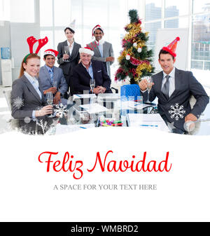 Portrait of a smiling business team wearing novelty Christmas hat  against feliz navidad Stock Photo