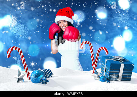 Woman wearing red boxing gloves against christmas scene with gifts and candy canes Stock Photo