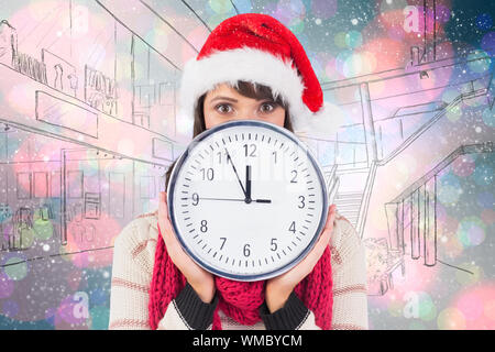 Festive brunette holding a clock against light glowing dots on blue Stock Photo