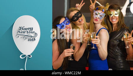 Attractive women wearing masks holding champagne against classy new year greeting Stock Photo