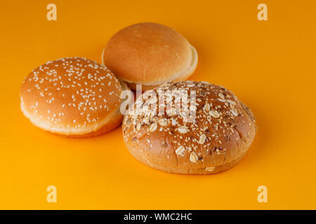 Rye and classic bun empty isolated. American food classic rye round burger bread isolated on orange background. Three different fried hamburger bun to Stock Photo