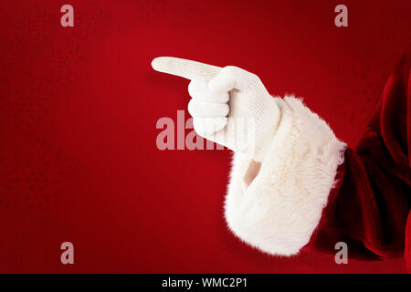 Santa Claus points at something against red background Stock Photo