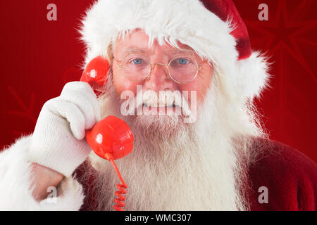 Santa on his red phone against red background Stock Photo