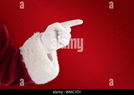 Santa Claus points at something against red background Stock Photo