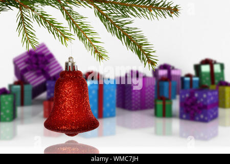 Red christmas decoration hanging from branch against many colourful christmas gift boxes Stock Photo