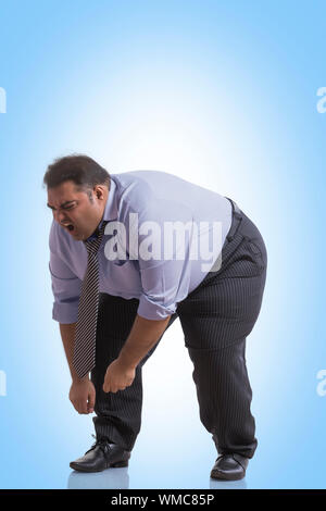 Obese man in formal clothes bending forward in pain Stock Photo