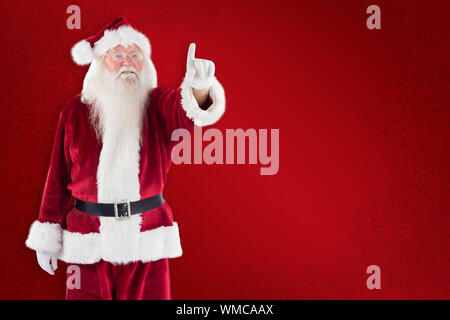Santa Claus points at something against red background Stock Photo