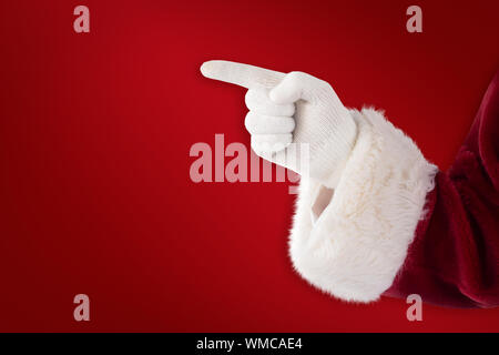 Santa Claus points at something against red background Stock Photo