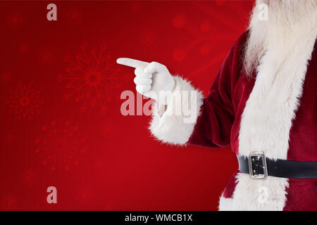 Santa Claus points at something against red background Stock Photo