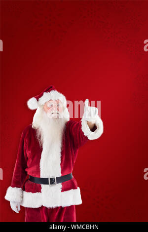 Santa Claus points at something against red background Stock Photo