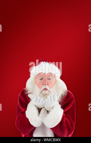 Santa Claus blows something away against red background Stock Photo
