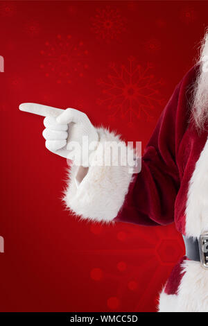 Santa Claus points at something against red background Stock Photo