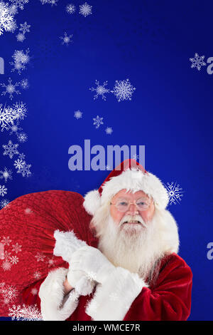 Jolly Santa carries his sack against blue Stock Photo