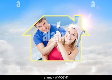 Hugging couple having fun while painting a room against blue sky with white clouds Stock Photo