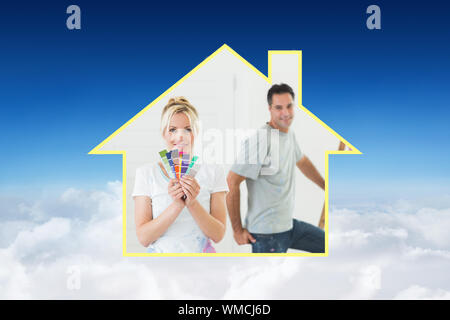 Couple with color swatches and ladder in a new house against blue sky over clouds Stock Photo