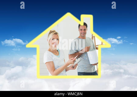 Couple with color swatches and ladder in a new house against bright blue sky over clouds Stock Photo