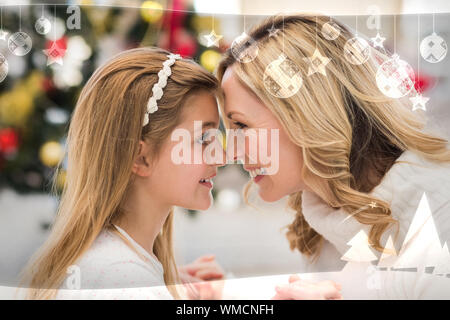 Festive mother and daughter beside christmas tree against christmas themed frame Stock Photo