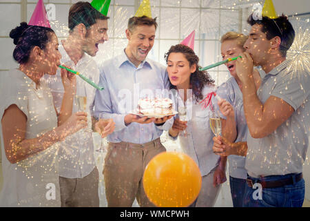 Casual businessmen team celebrating a birthday against colourful fireworks exploding on black background Stock Photo