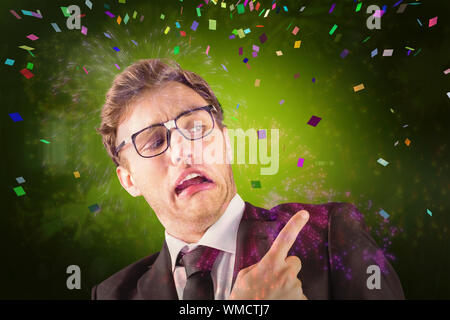 Young geeky businessman pointing to shoulder against colourful fireworks exploding on black background Stock Photo