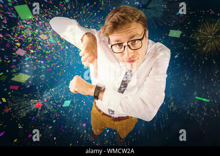 Geeky businessman pointing to watch against colourful fireworks exploding on black background Stock Photo