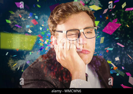 Young geeky businessman looking bored against colourful fireworks exploding on black background Stock Photo