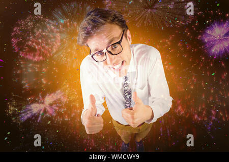 Young geeky businessman showing thumbs up against colourful fireworks exploding on black background Stock Photo