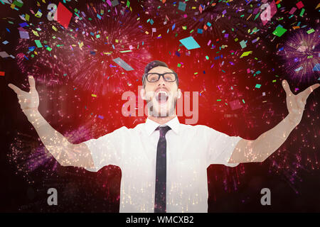 Geeky young businessman with arms out against colourful fireworks exploding on black background Stock Photo