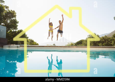 Cheerful couple jumping into swimming pool against house outline Stock Photo