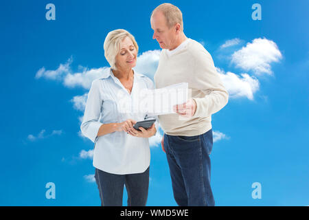 Mature couple working out their bills against cloudy sky Stock Photo