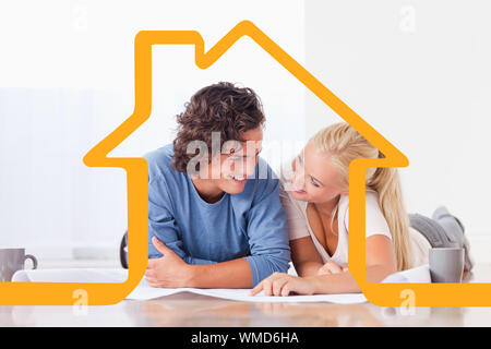 Smiling couple moving in a new house against house outline Stock Photo