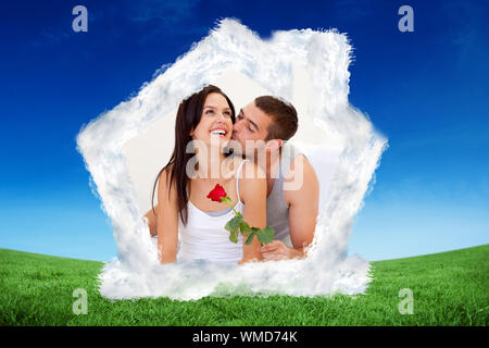 Lovers sitting on bed with a rose against green field under blue sky Stock Photo